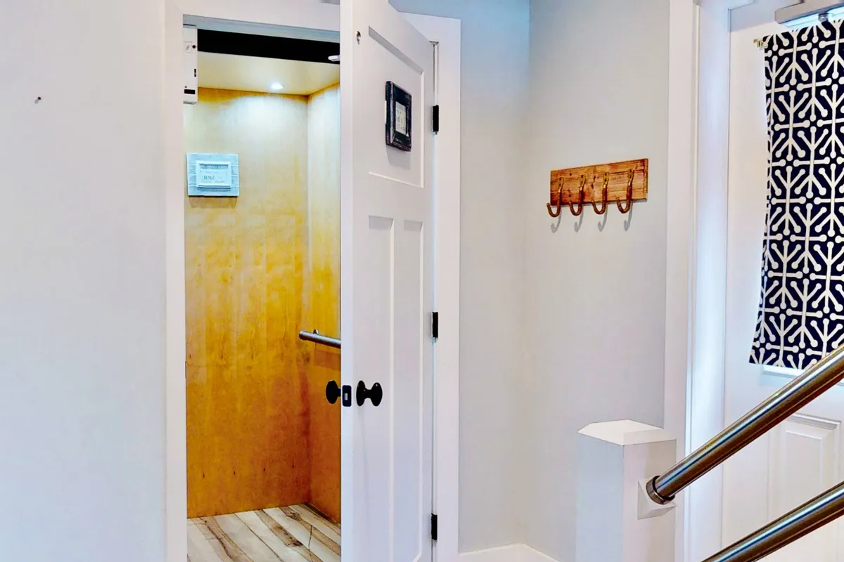 A modern elevator door situated in a stylish hallway with decorative elements including wall hooks and a patterned curtain. The space is functional yet aesthetically pleasing, signaling the convenience and exclusivity of private access to the top floor.