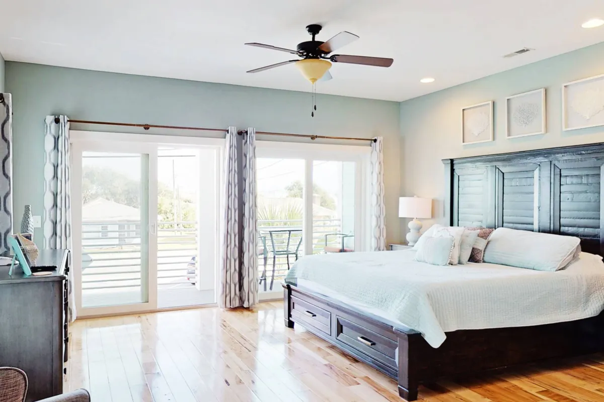 A tranquil bedroom featuring a comfortable bed, large windows letting in plenty of natural light, decorative wall art, and access to a balcony. The atmosphere is peaceful and inviting, perfect for a restorative night's sleep or quiet morning moments.
