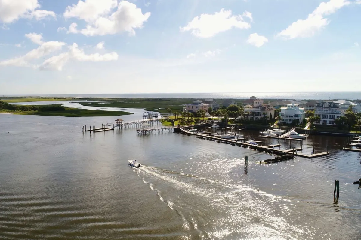 A peaceful marina scene featuring calm waterways, boats docked alongside upscale homes, and a wide sky. The setting is perfect for sunset boat rides, exploring nearby islands, or simply relaxing by the water.